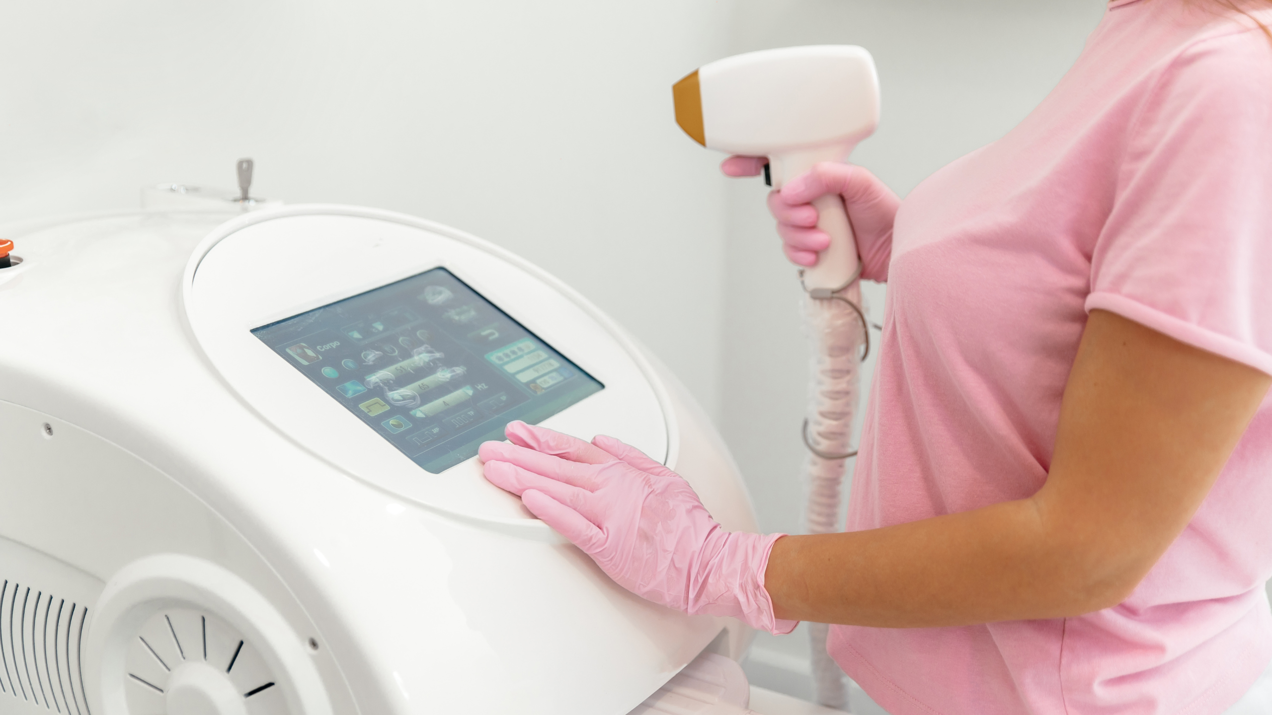 laser hair removal machine with woman in pink scrubs holding the laser